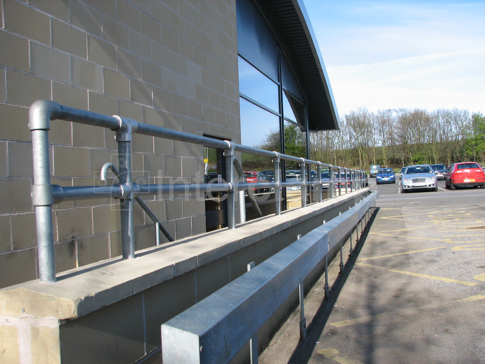 A galvanised key clamp guardrail constructed on top of a concrete wall at a service station